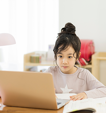 little girl sitting in front of a laptop